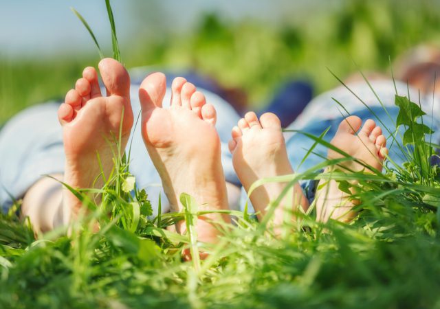 Adult's and child's bare feet on green summer grass as a grounding technique for anxiety