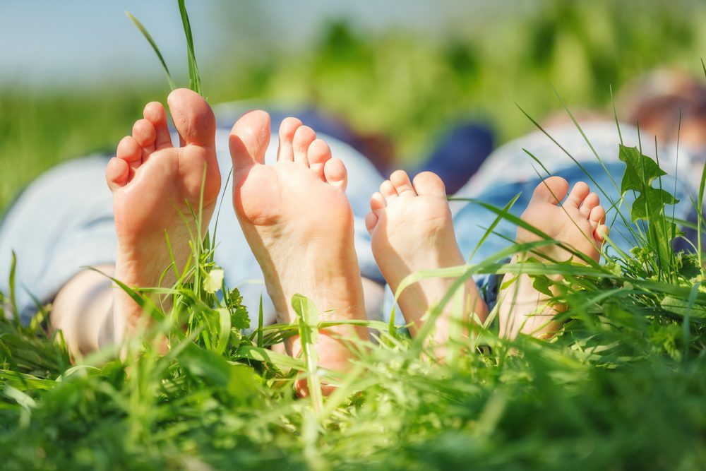 Adult's and child's bare feet on green summer grass as a grounding technique for anxiety