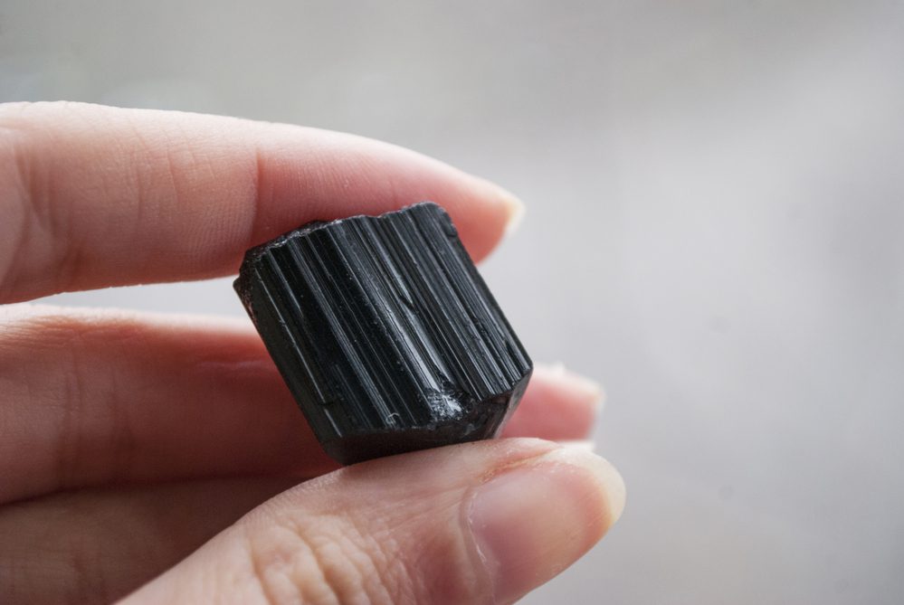 A piece of crystal of natural stone black tourmaline in hand