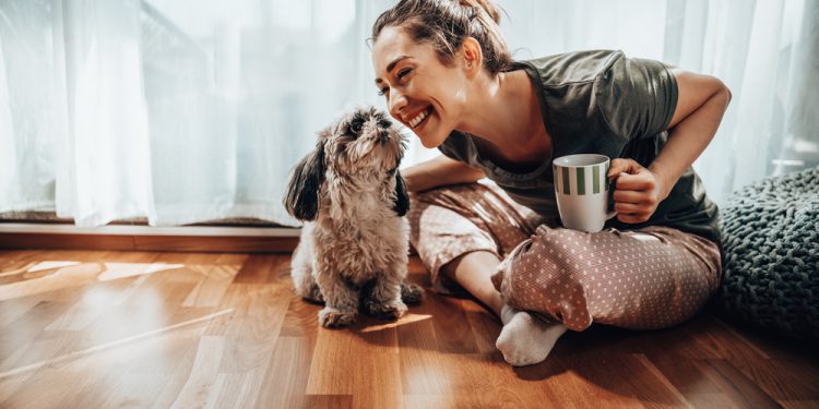 Young smiling woman enjoying coffee with her Shih Tzu dog in the cozy morning at home after learning how to get out of bed when depressed