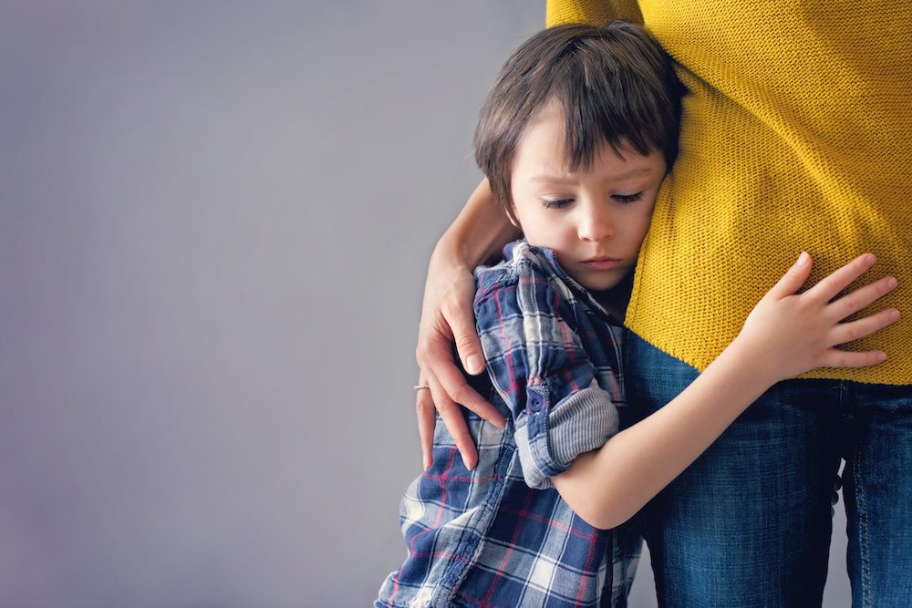 Sad little child, boy, hugging his mother at home, isolated image, copy space. Family concept dealing with anxiety triggers