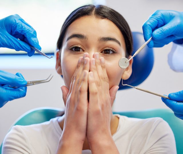 Woman, dental patient and scared or shock (dental fear) for healthcare, portrait and medical surgery. Female person, overwhelmed or dentist hand with tools, frightened anxiety for toothache or fear in chair.