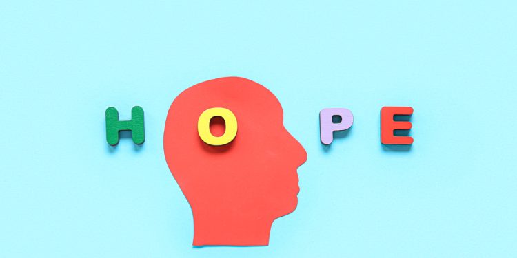 Paper human head and word HOPE made of wooden letters on blue background. Mental Health Day