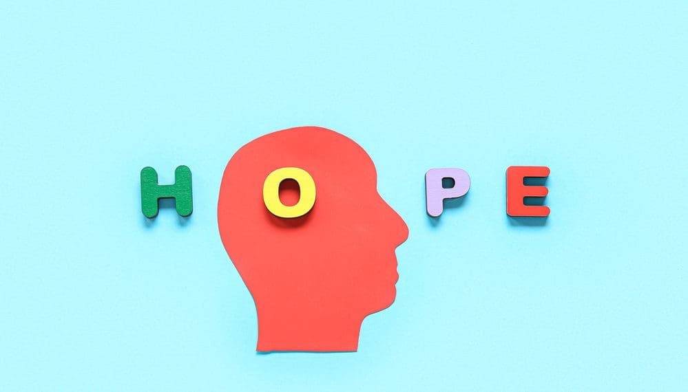 Paper human head and word HOPE made of wooden letters on blue background. Mental Health Day