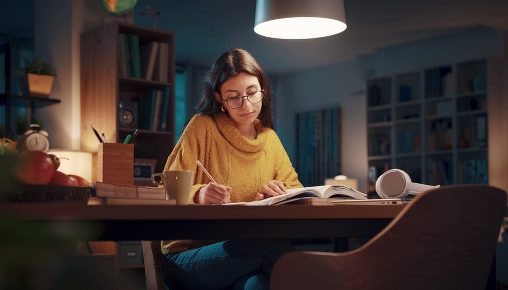 Young university student reading books late at night, she is studying and preparing for her exams, experiencing study stress and looking for study tips, such as fidget rings, worry stones and other spiritual gifts