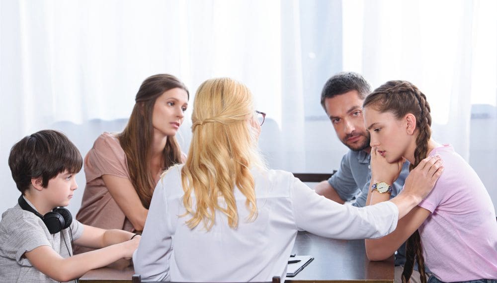A compassionate family therapist in Rhode Island guiding a family through counseling in a warm, supportive setting.