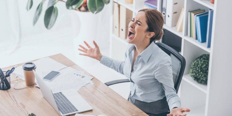 A woman practicing mindfulness at her desk, balancing career growth and mental health with self-care tools like a fidget ring and a calming workspace.