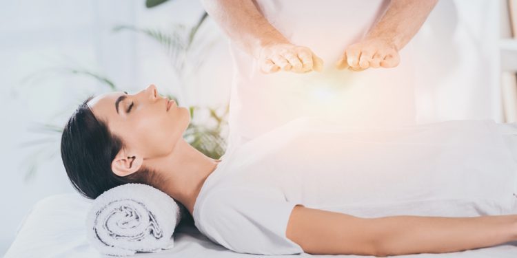 A person holding a worry stone while practicing grounding techniques for anxiety, symbolizing the connection between trauma and anxiety relief through self-care items and relaxation gifts like fidget rings,